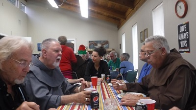 Clergy and parishioners seated together enjoy a pot luck